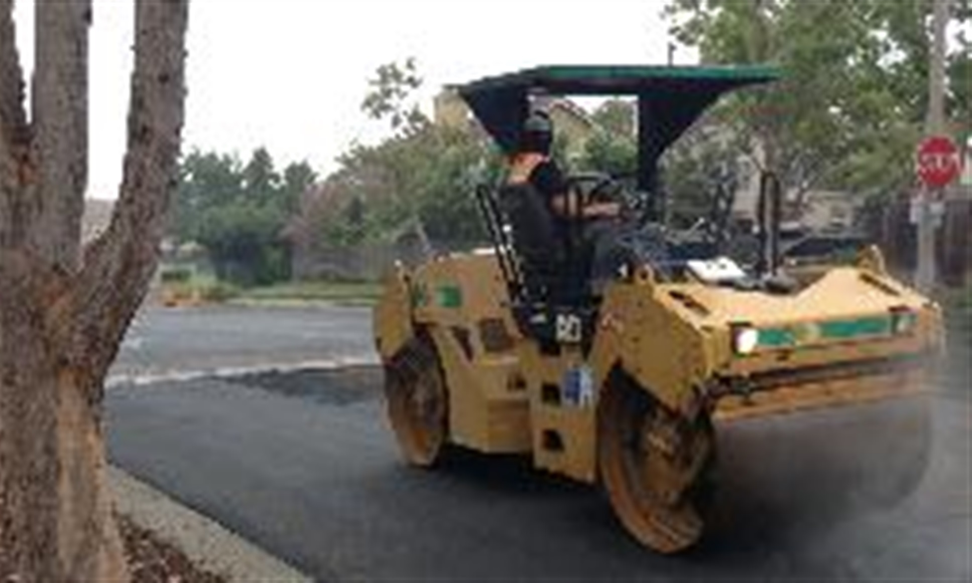 Construction crew smoothing new street pavement