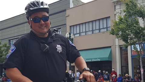 An APD Police Officer Smiling for the camera as he rides his bike during the 4th of July Parade