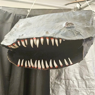 Shark attack! Shark sculpture suspended from the ceiling, sharp teeth and mouth open. Imagined and created by teens!