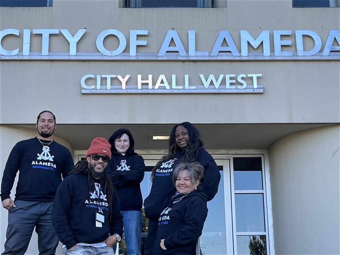 Five members of the Engagement or Outreach Team smiling in front of City Hall West