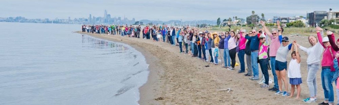 Community members holding hands at the shoreline