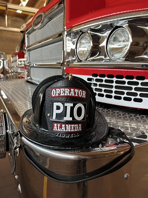 Fire helmet with PIO shield on the bumper of a fire truck